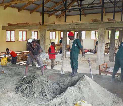 Bauarbeiter-schüler zementieren den Boden in unserer Tischlerei